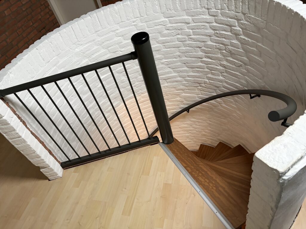 Zwarte balustrade met spijlen en staander bij vloeropening spiltrap